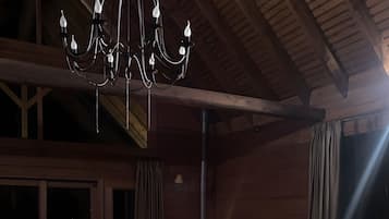 Une pièce chaleureuse avec un plafond en bois, un lustre, une cheminée et une bibliothèque.