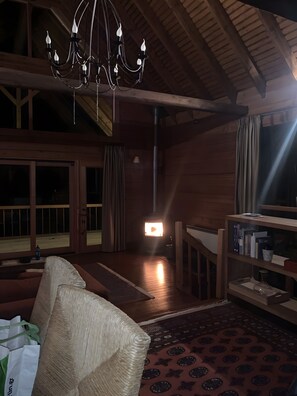 Ein gemütliches Zimmer mit Holzboden, einer Kristallleuchter, einem Kamin und einem Bücherregal.