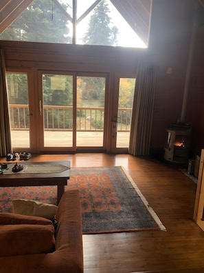 Ein gemütliches Zimmer mit einer großen Holztür, die auf eine Terrassenausläufer führt, einem Kamin und einem gemusterten Teppich.