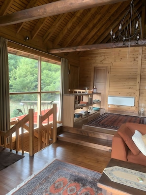 A wooden cabin interior with a large window, wooden staircase, and a cozy seating area. - Chalet 'Xephoto' with Mountain View and Balcony (Αράχοβα)