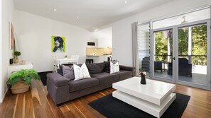 Una sala de estar moderna con un sofá gris, una mesa de centro blanca y una zona de comedor con una mesa y sillas blancas.