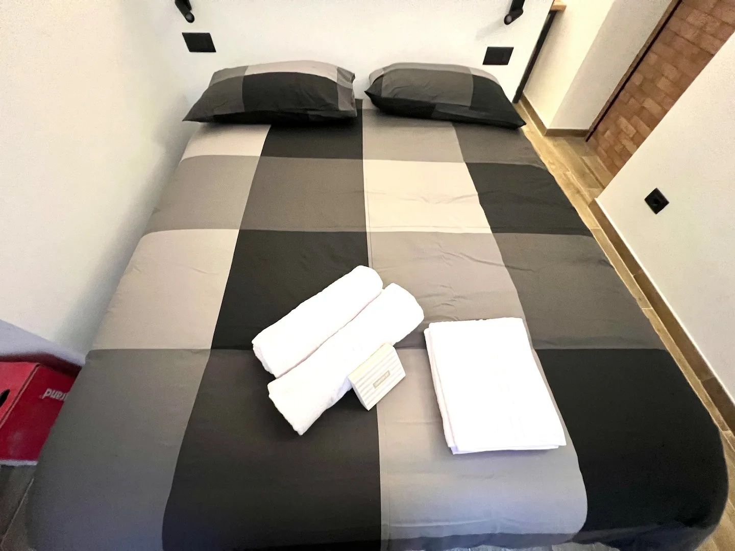 A bed with a checkered bedspread, two pillows, and neatly folded white towels.