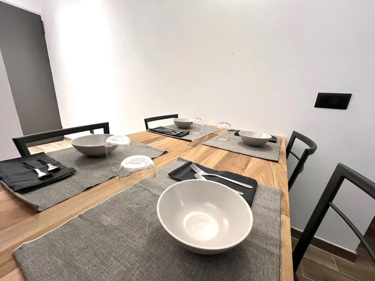 A dining table set with bowls, cutlery, and placemats.