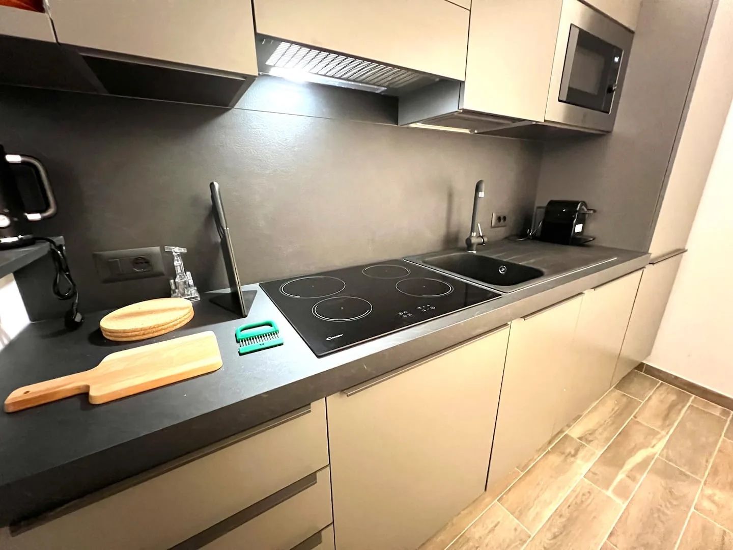 A modern kitchen with a black countertop, stainless steel appliances, and a microwave above.