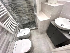 A modern bathroom with a glass shower enclosure, a freestanding sink, and a vanity with a cabinet. - New Listing (Sanremo)