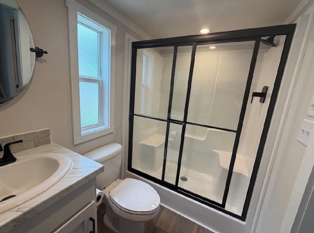 A bathroom with a white sink, toilet, and a glass-enclosed shower area.