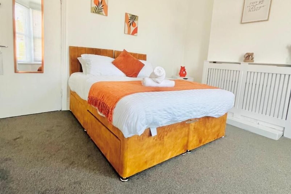 Een slaapkamer met een bed, een radiator en een deur.