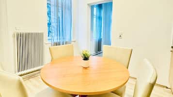Een ronde tafel met vier stoelen in een kamer met witte muren en een radiator.