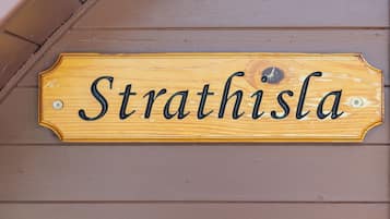 Een houten bord met de naam 'Strathisla' op een muur bevestigd.