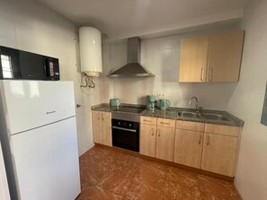 Una cocina compacta con refrigerador, estufa, pileta y alacenas.