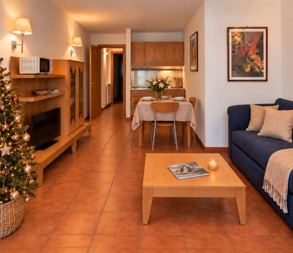 A cozy living room with a television, a coffee table, and a Christmas tree.