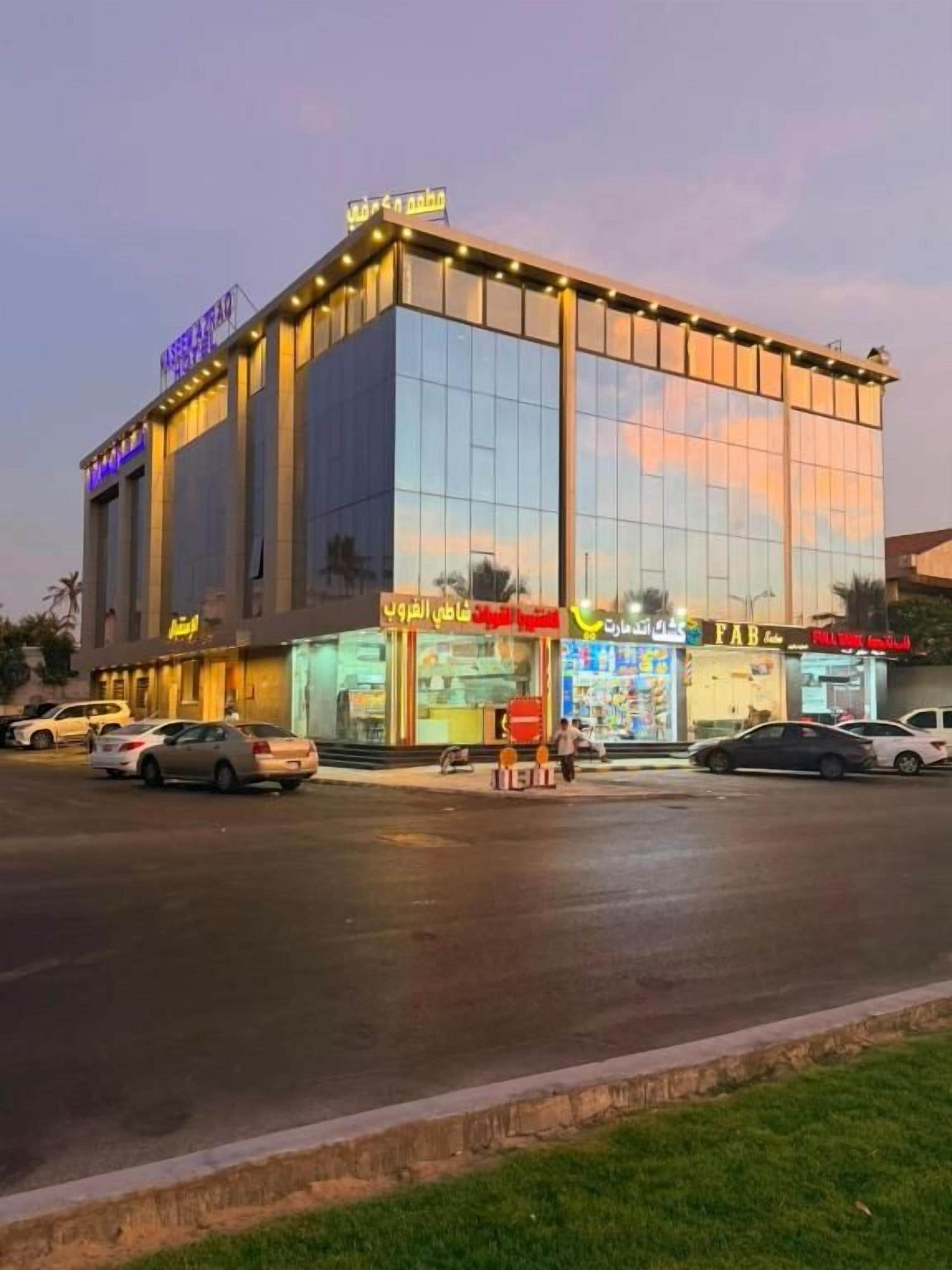 Un bâtiment moderne doté d’une façade en verre, de nombreuses vitrines et d’un parking.