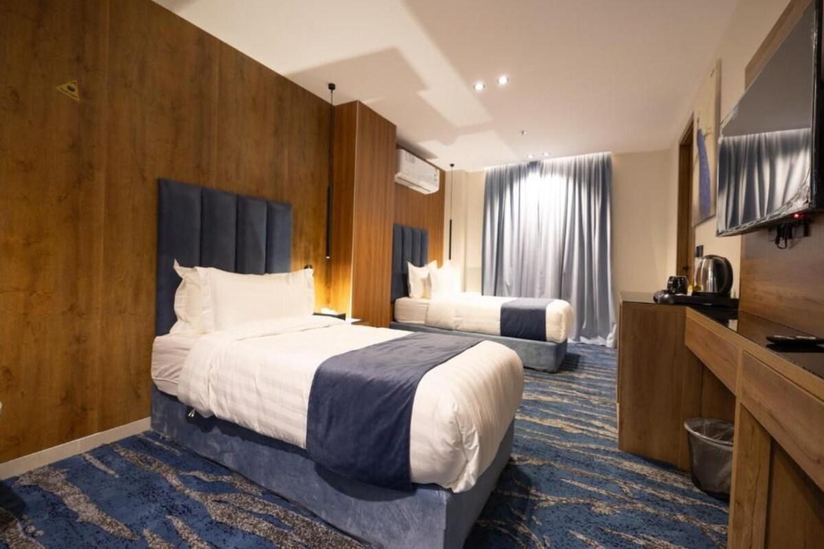 A hotel room with a large bed, a smaller bed, a desk, and a television.