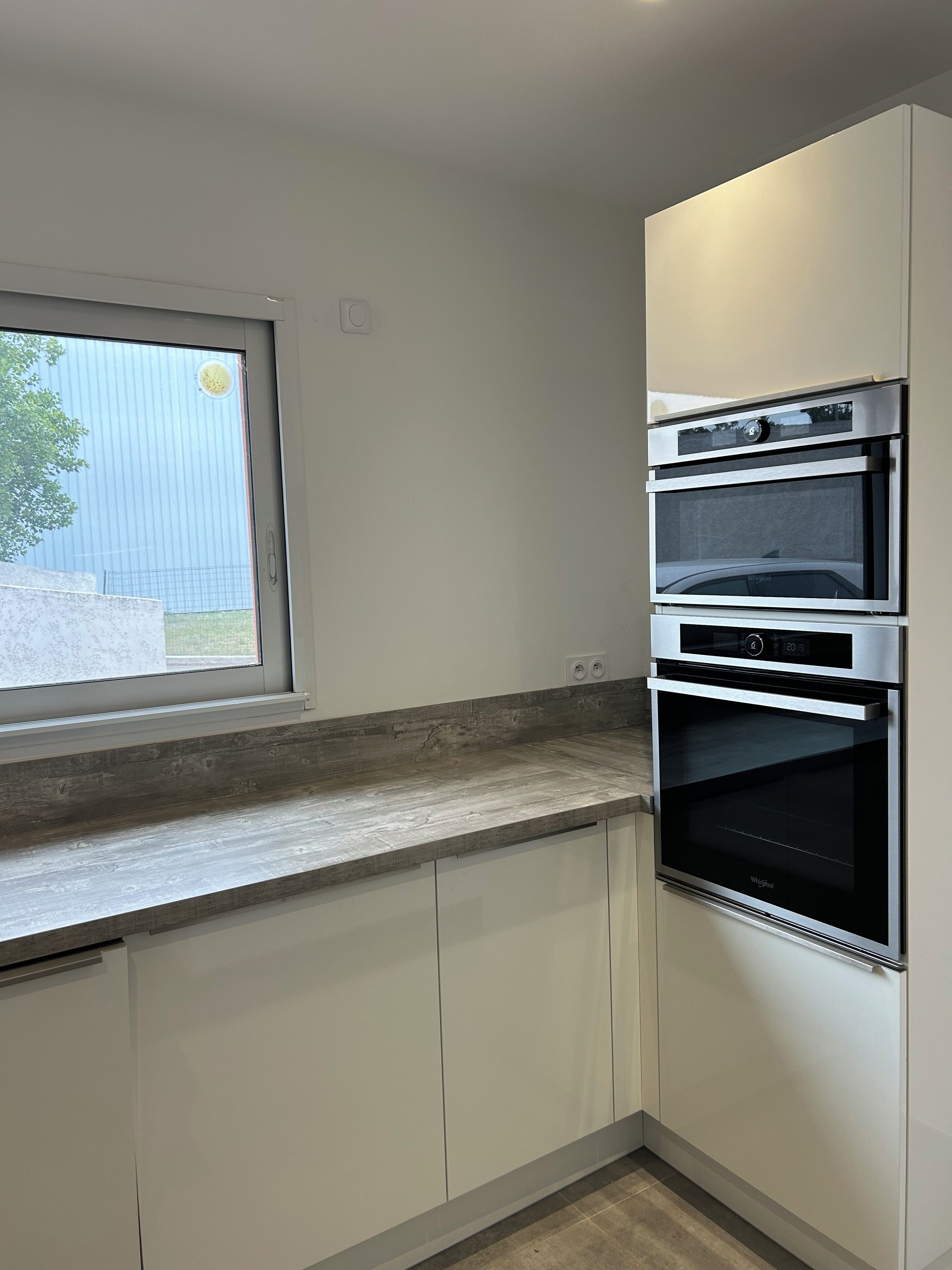 A kitchen with a built-in oven and a window.