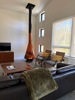 Uma sala de estar moderna com lareira, sofá, mesa de centro e televisão.