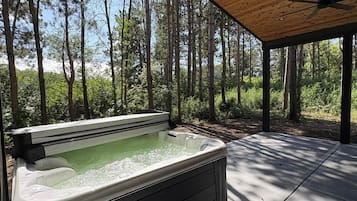 Jacuzzi en una estructura de fusta a l'aire lliure amb vista a un bosc.