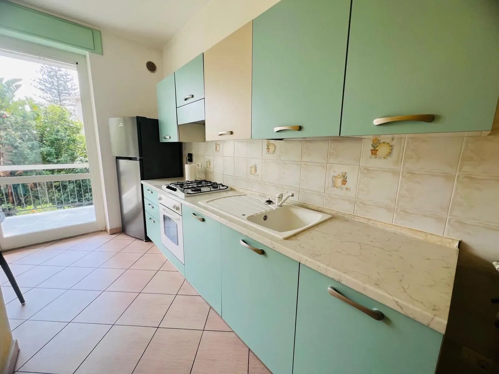 A kitchen with teal cabinets, a gas stove, and a sink.
