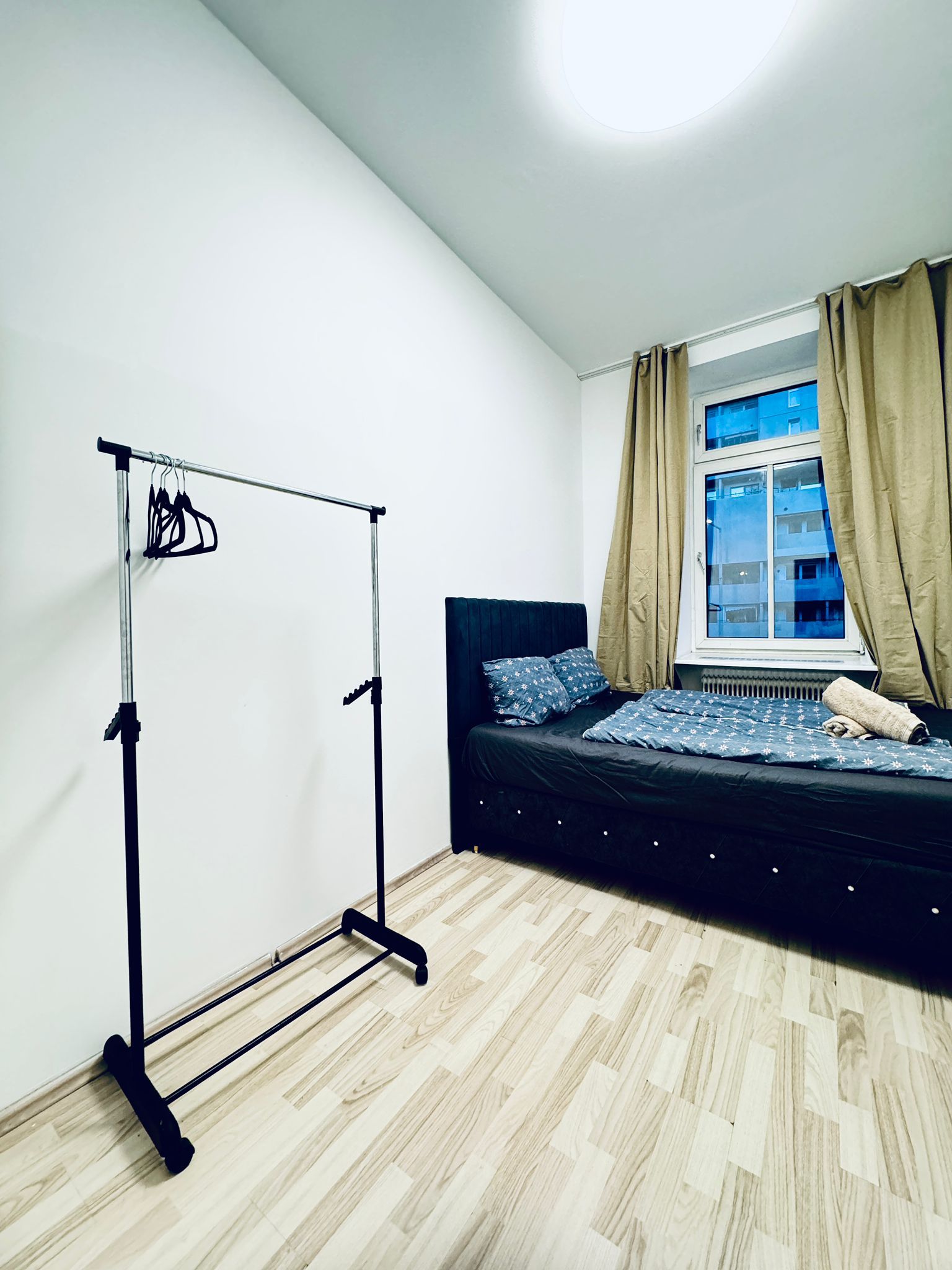 Een slaapkamer met een bed, een kledingkast, een raam met gordijnen en een lamp.