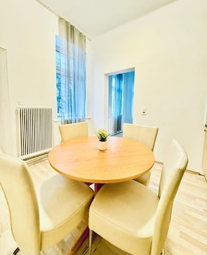 Een ronde tafel met vier stoelen in een kamer met witte muren en een radiator.