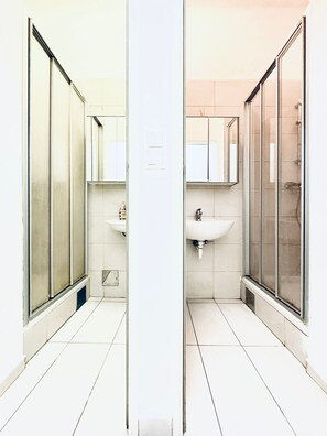 Une salle de bain moderne avec une douche à parois de verre, un lavabo blanc et un miroir au-dessus du lavabo.