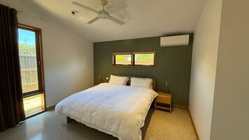 A bedroom with a bed, a nightstand, a ceiling fan, and a window.