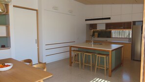 Una cocina compacta con una isla central, una mesa de comedor con sillas y un refrigerador.