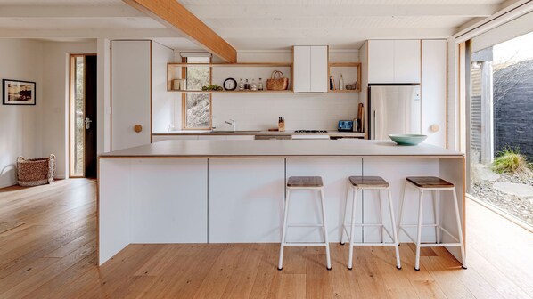 Una cocina moderna con una isla grande, taburetes de bar y vistas al exterior.