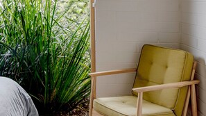 Un coin de pièce avec un fauteuil jaune recouvert de tissu et un mur en briques blanches.