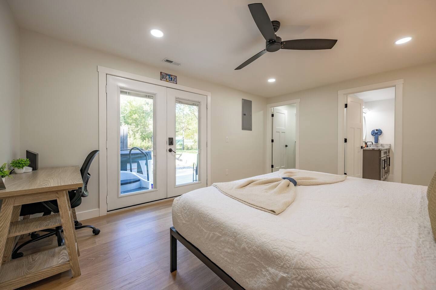 A bedroom with a bed, a desk, and a chair. There is a door leading to a balcony.