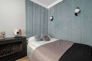 Quarto com cama, lareira e luminária fixada na parede.