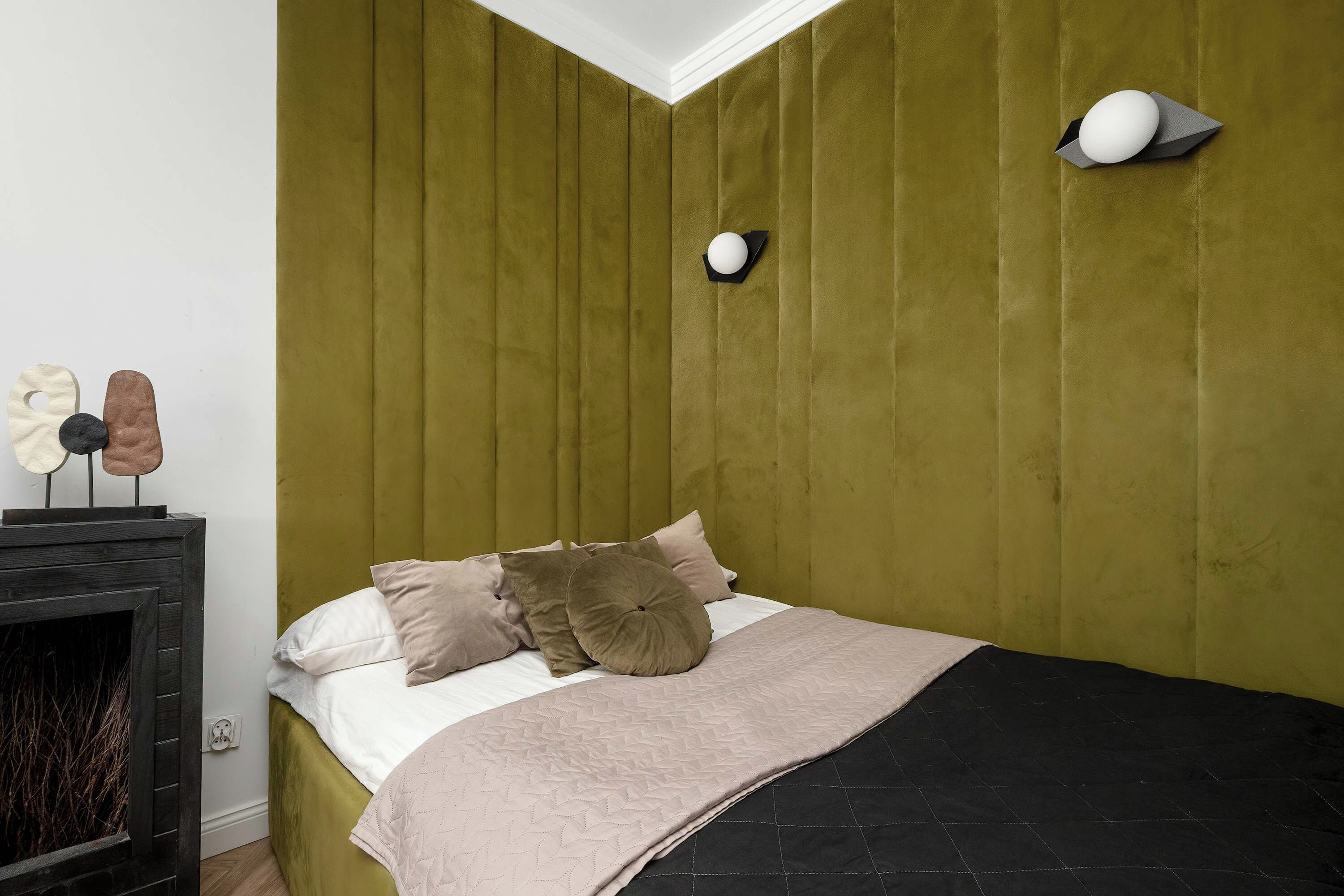 Ein Schlafzimmer mit einem Bett, Kissen, einem Nachttisch und einer Wandlampe.