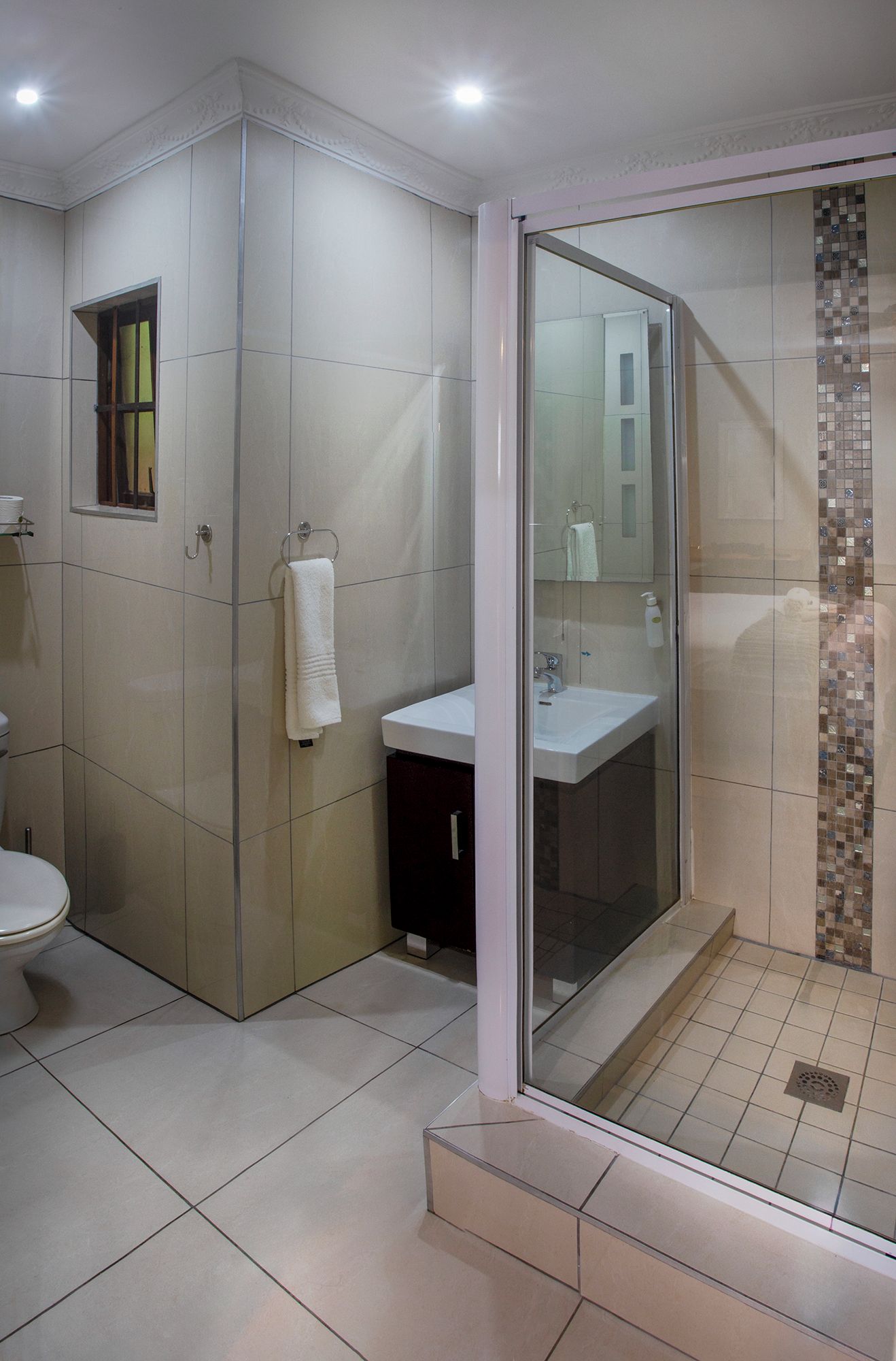 Uma casa de banho moderna com chuveiro envidraçado, lavatório branco e sanita.