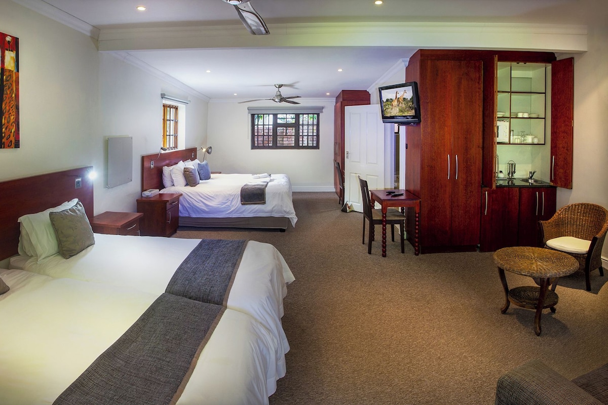 A hotel room with two beds, a desk, a chair, a television, and a wardrobe.