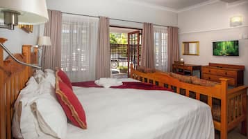 Een hotelkamer met een groot bed, een bureau, een stoel, een televisie en een raam met gordijnen.