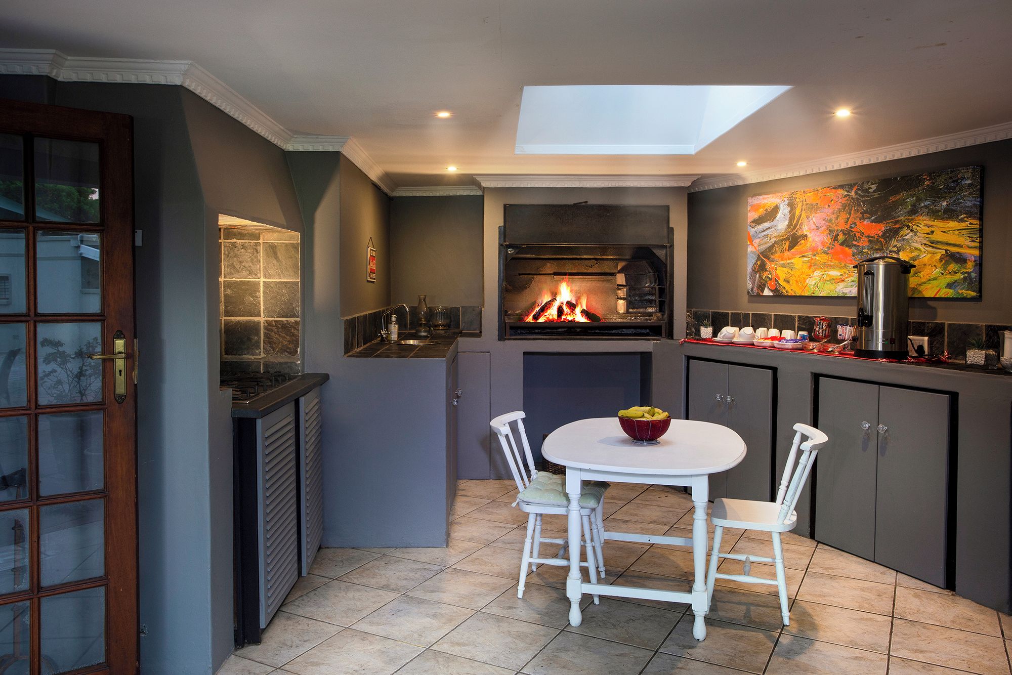 Een keuken met een ingebouwde open haard, een eettafel met stoelen en een schilderij aan de muur.
