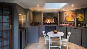 Een keuken met een ingebouwde open haard, een eettafel met stoelen en een schilderij aan de muur.