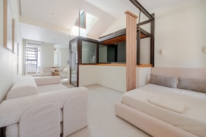 Une chambre à coucher moderne avec un lit de style industriel, un canapé et un coin repas.