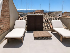 A rooftop terrace with two lounge chairs, a small table, and a brick wall. - Holiday Home 'Breakfast in The Sun Urban Oasis' with Mountain View and Wi-Fi (Granada)