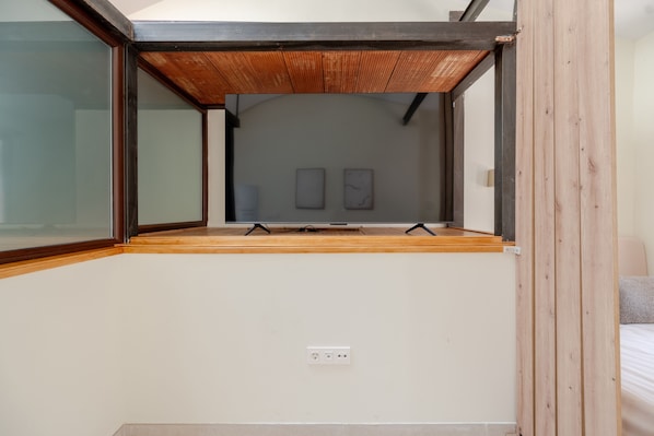 Une pièce avec un plafond en pente, un plancher en bois et une seule prise de courant sur le mur.