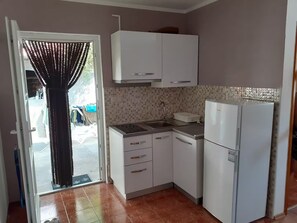 Una cucina compatta con mobili bianchi, forno integrato e frigorifero.