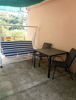 A balcony with a striped bench, a table, and two chairs. - studio Jasna (Kukljica)