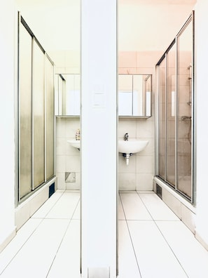 Un bagno moderno con box doccia in vetro, lavandino bianco e specchio sopra il lavandino.