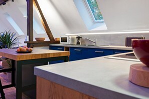 A modern kitchen with a skylight, a wooden table with fruit, and a built-in microwave.