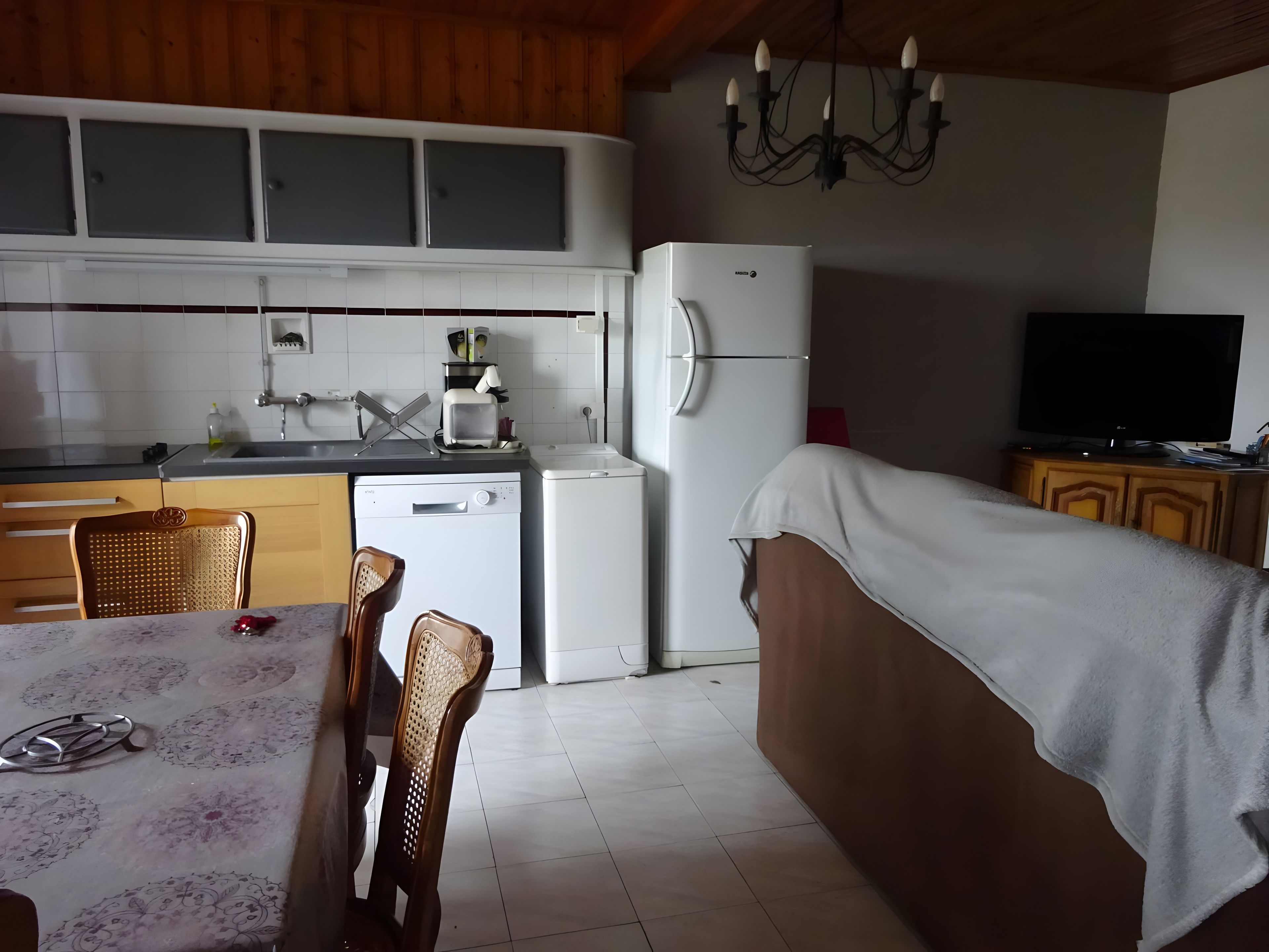 Una cocina compacta con refrigerador, lavavajillas y un comedor con sillas y mesa.