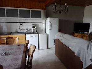 A compact kitchen with a refrigerator, dishwasher, and a dining area with chairs and a table. - House on the Chemin de Régordane (Landos)