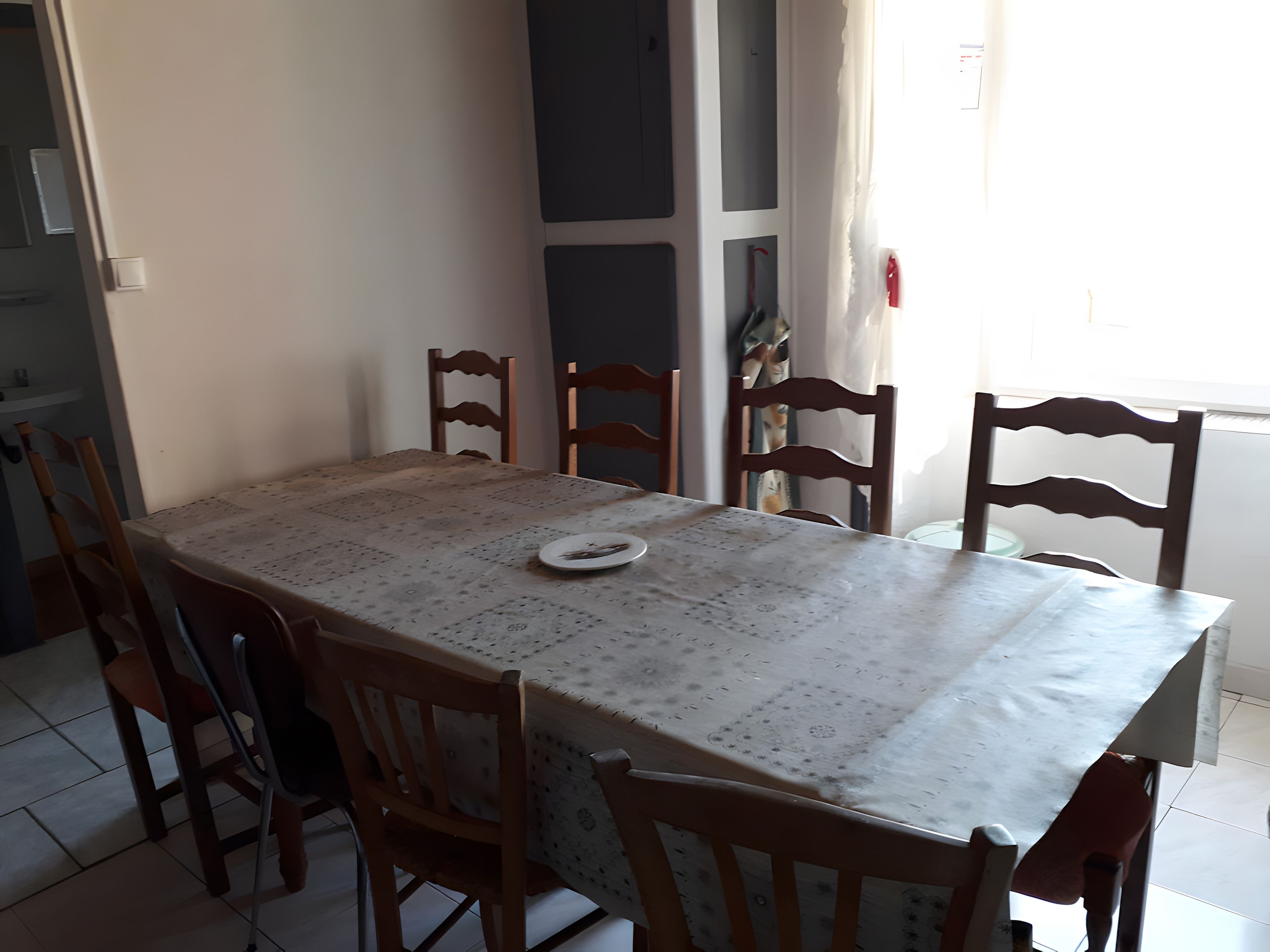 A dining table with a patterned tablecloth, surrounded by six wooden chairs.