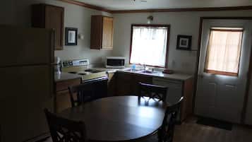 A compact kitchen with a dining table, chairs, a refrigerator, a microwave, and a sink.