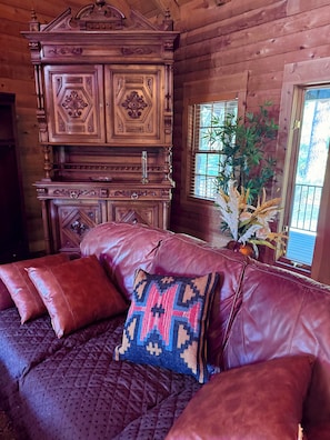 Un intérieur en bois avec un canapé en cuir, des panneaux décoratifs et une fenêtre agrémentée d’une plante.