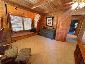 Une pièce chaleureuse avec un plafond en bois, un banc, une commode et une porte donnant sur une autre pièce.