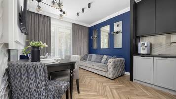 Ein modernes Wohnzimmer mit einer Couch, einem Esstisch und Stühlen. Es gibt eine Küchenzeile mit Schränken und einer Arbeitsplatte.